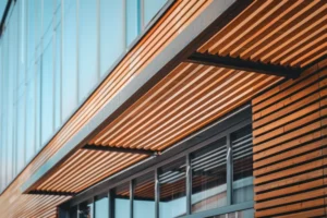 Horizontal wood slat sunshade awning integrated into glass and timber building facade