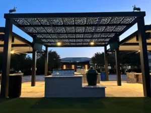 Patterned pergola creates a twilight-ready outdoor kitchen with layered textures and ambient lighting