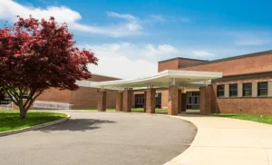 White canopy supported by brick columns over curved driveway at school entrance